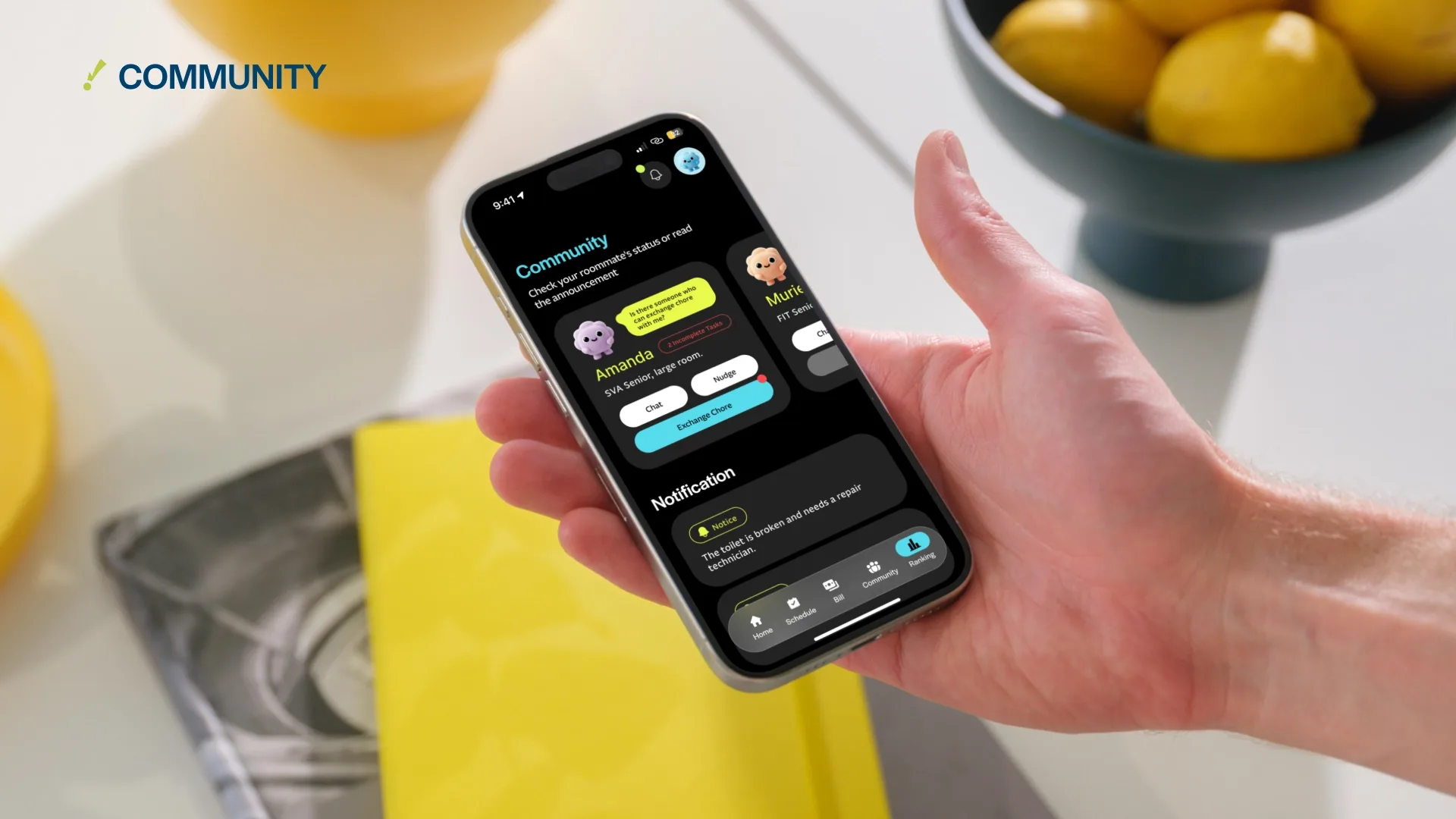 A hand holds a smartphone displaying the Community page, showing individual roommate profiles and notification alerts.